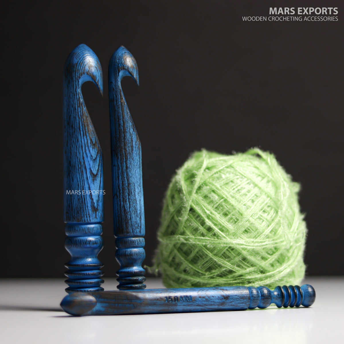 Three large antique blue wooden crochet hooks on dark background