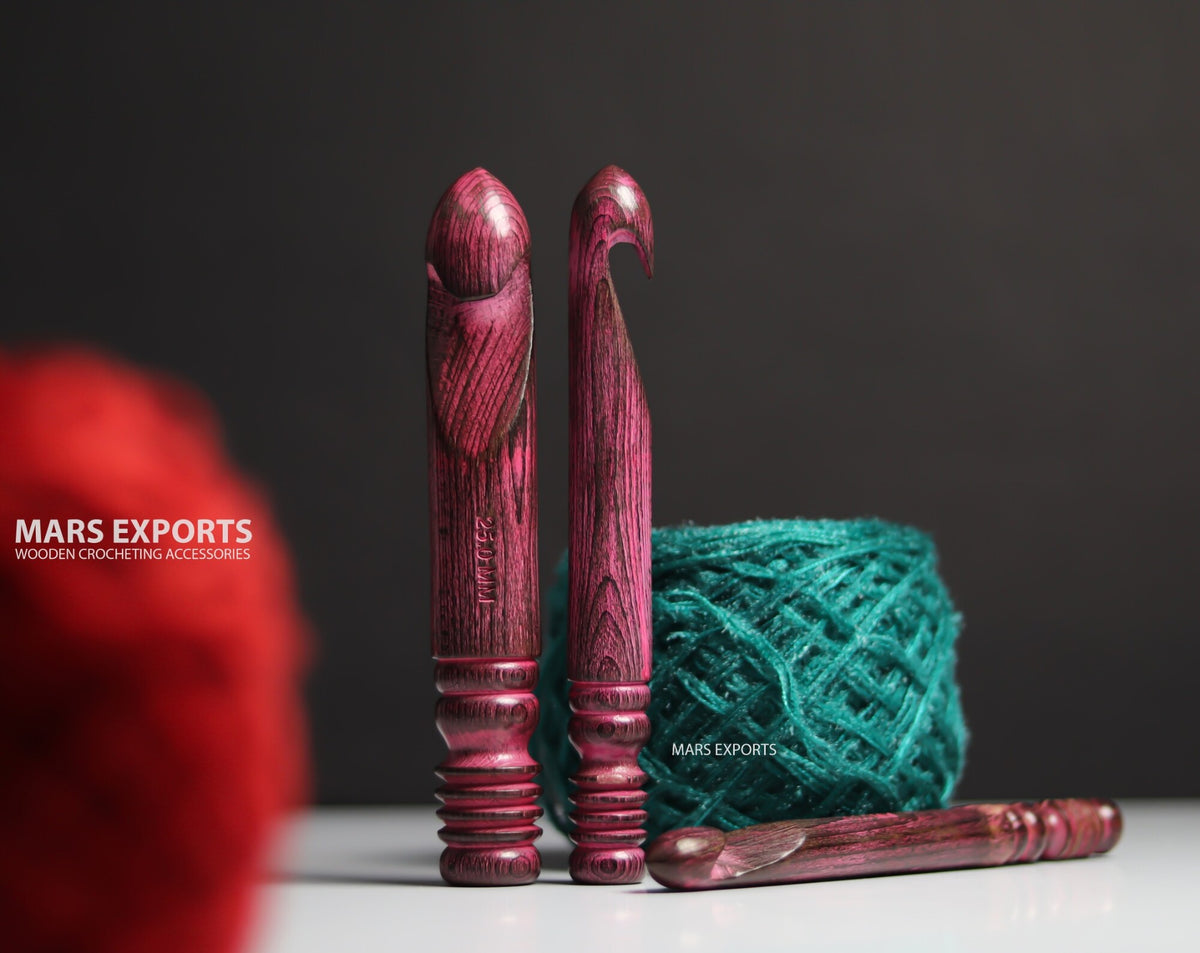 Three large wooden crochet hooks with antique red finish on dark background