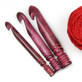 Three antique red wooden crochet hooks in 15 mm, 20 mm and 25 mm with yarn