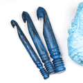 Three antique blue wooden crochet hooks in 15 mm, 20 mm and 25 mm with yarn